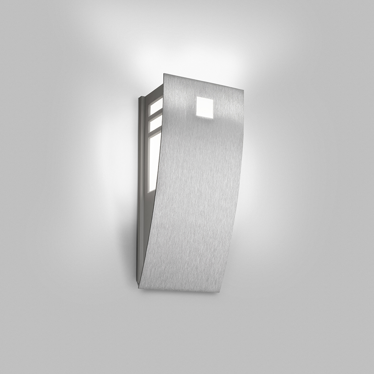 A wedge-shaped curved wall sconce with cutout accents in its solid body and uplighting