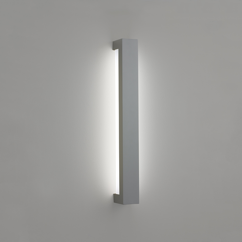 A linear wall sconce with a solid outer body and a luminous diffuser underneath