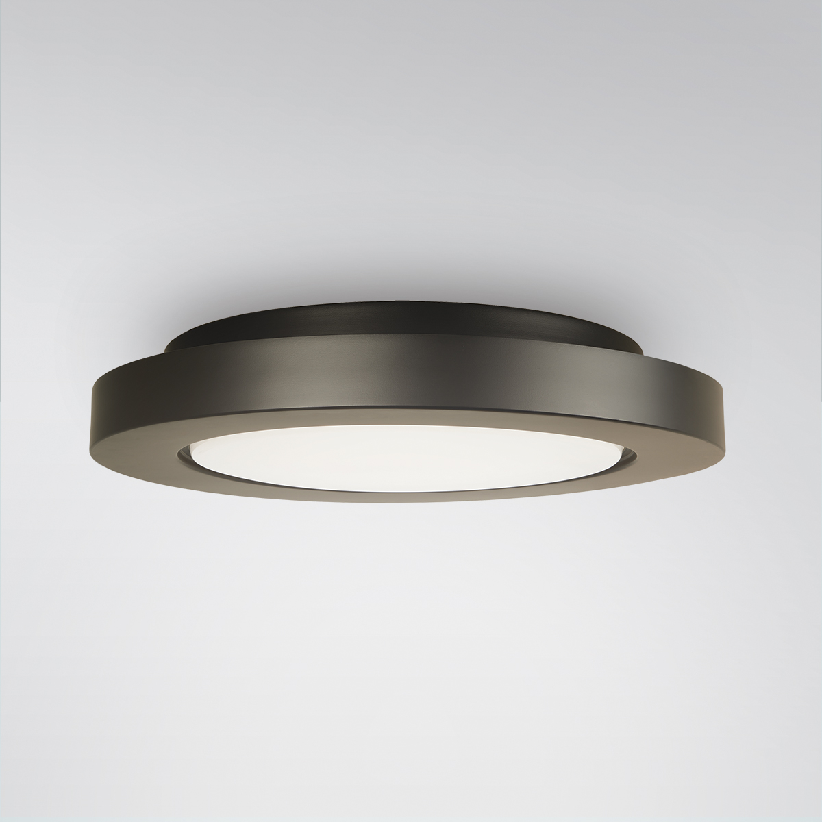 A circular ceiling-mounted luminaire with a dark painted finish and a luminous downlight