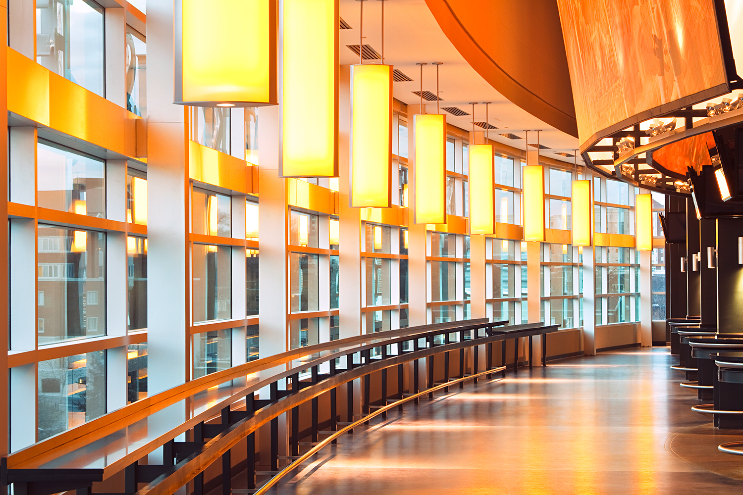 Air Foil education lighting fixtures hung along a stadium window in the university's unique orange color.