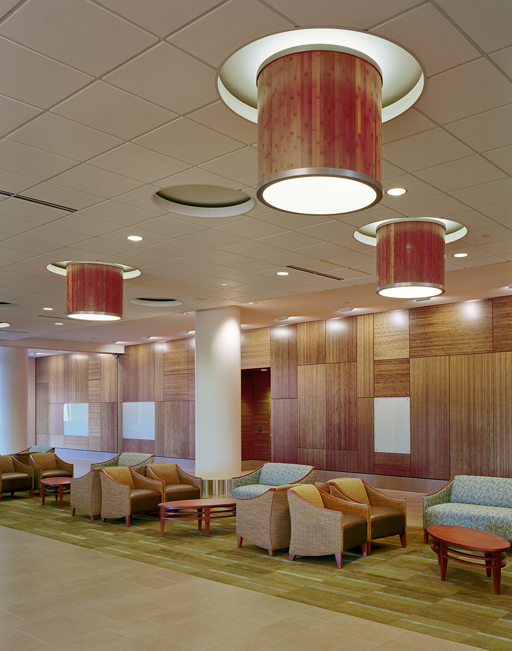 Large, wood-paneled custom light fixtures mounted above a warm waiting room.