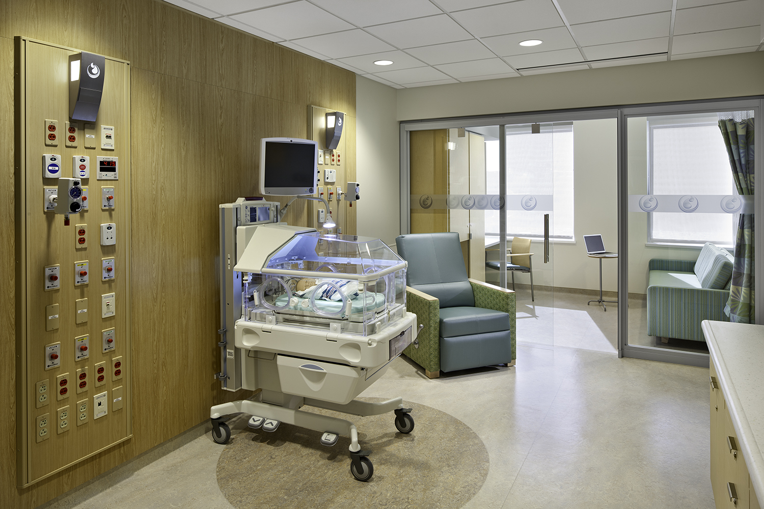 Cypress custom light fixtures in a NICU patient room, mounted on a wood paneled headwall.