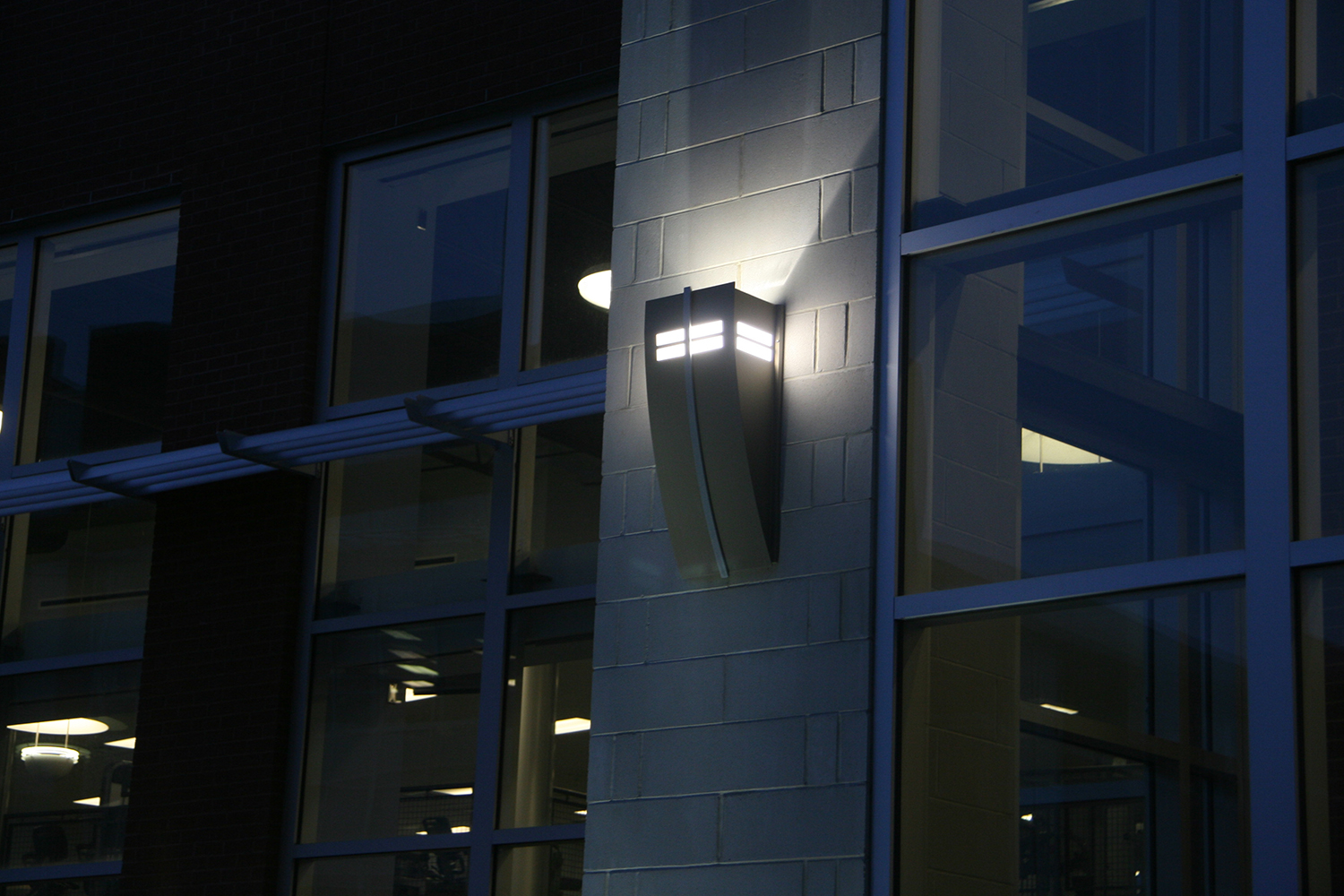 Cypress outdoor light fixture provides soft uplight between windows on a dark exterior