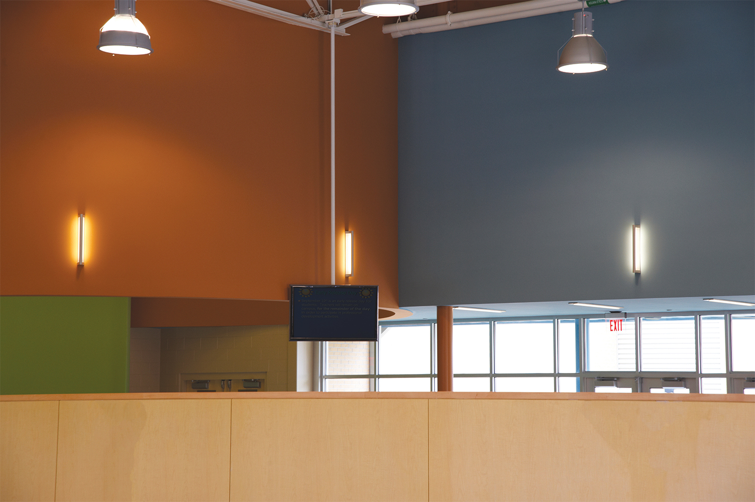 Ether wall-mounted luminaires along colorful classroom walls for a pleasing education lighting design.