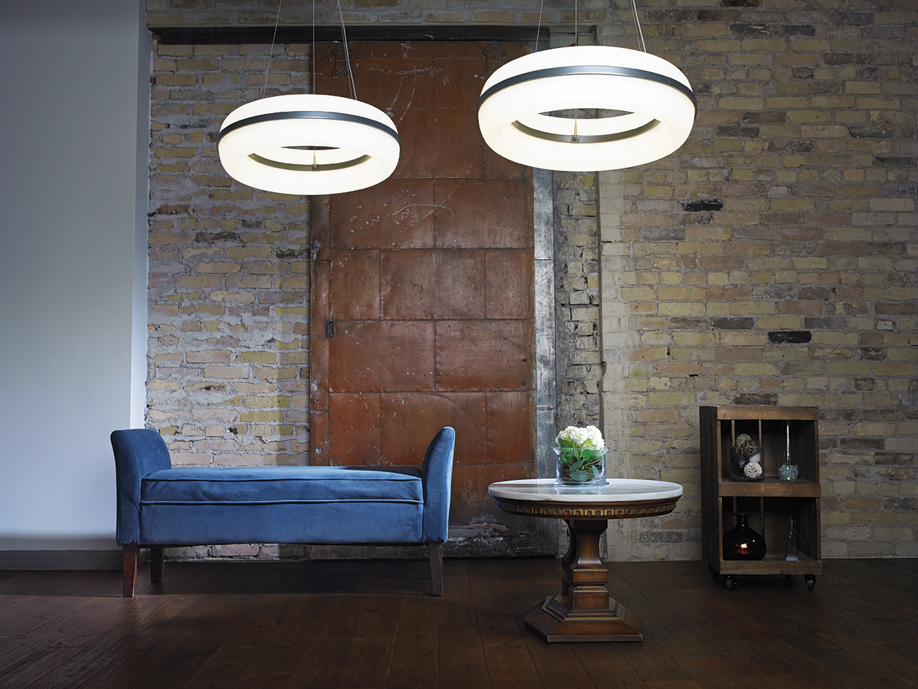 Meridian Round pendant is perfect for hospitality lighting, seen here above a blue sofa in a modern loft.