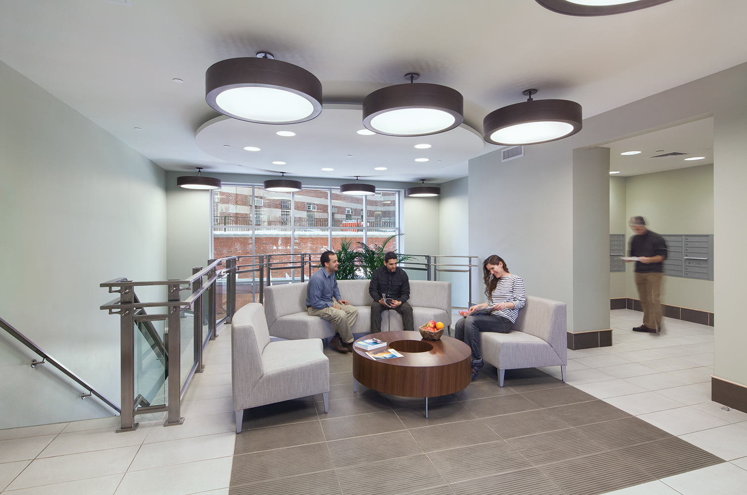 Omnience office lighting fixtures in a common seating area between a stairwell and a mailroom.