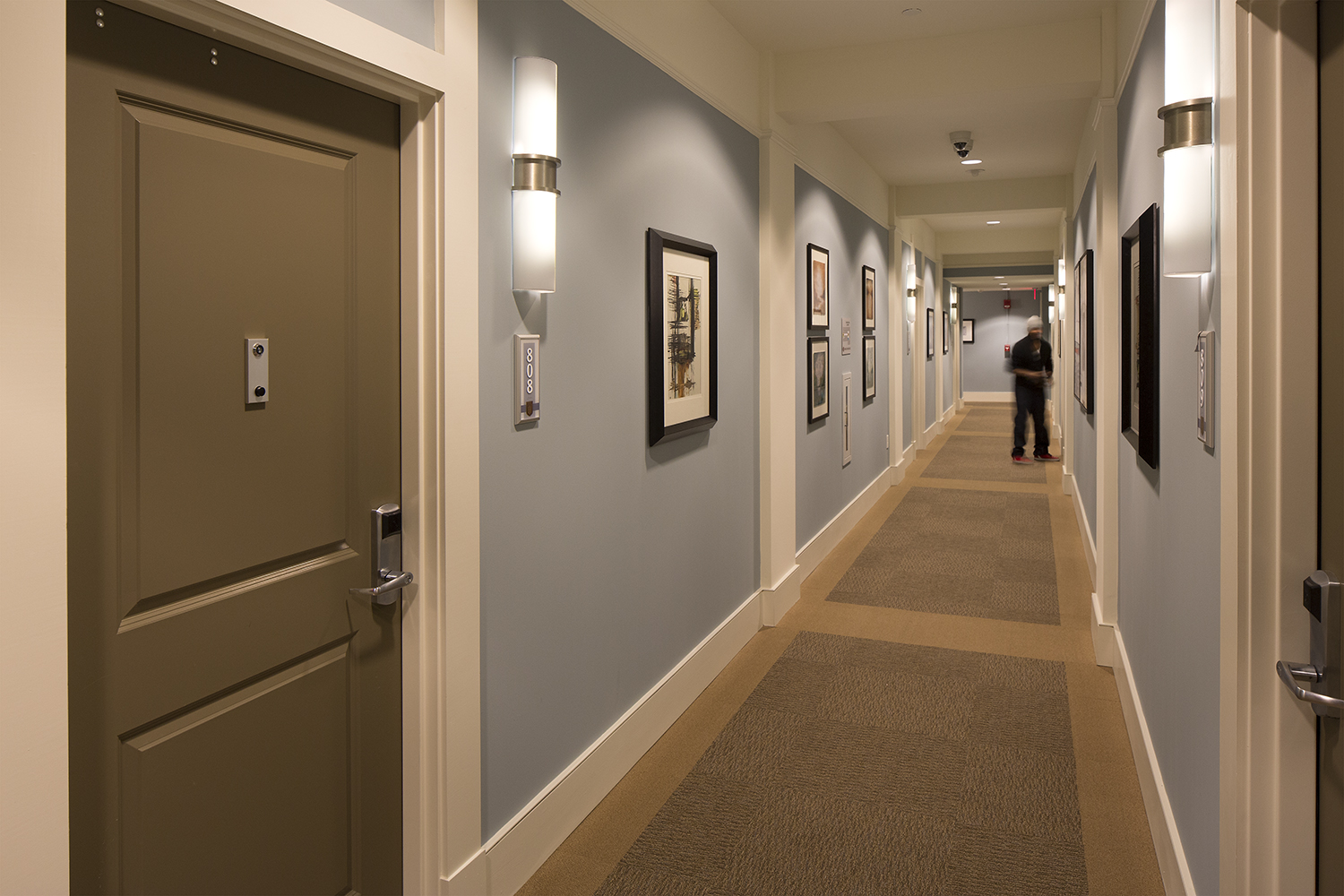 Pila sconces are ideal for hotel or apartment lighting applications, seen here alongside doors in a residential hallway.