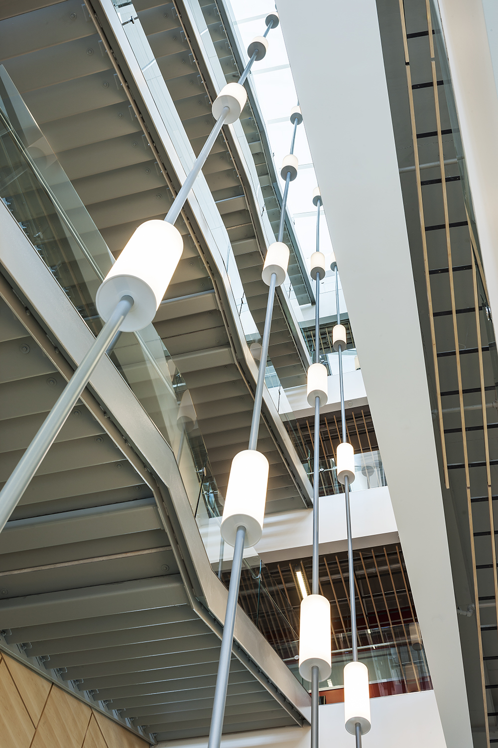 Sequence pendants enhance educational interior design in a tandem-mount configuration for a multi-level atrium.